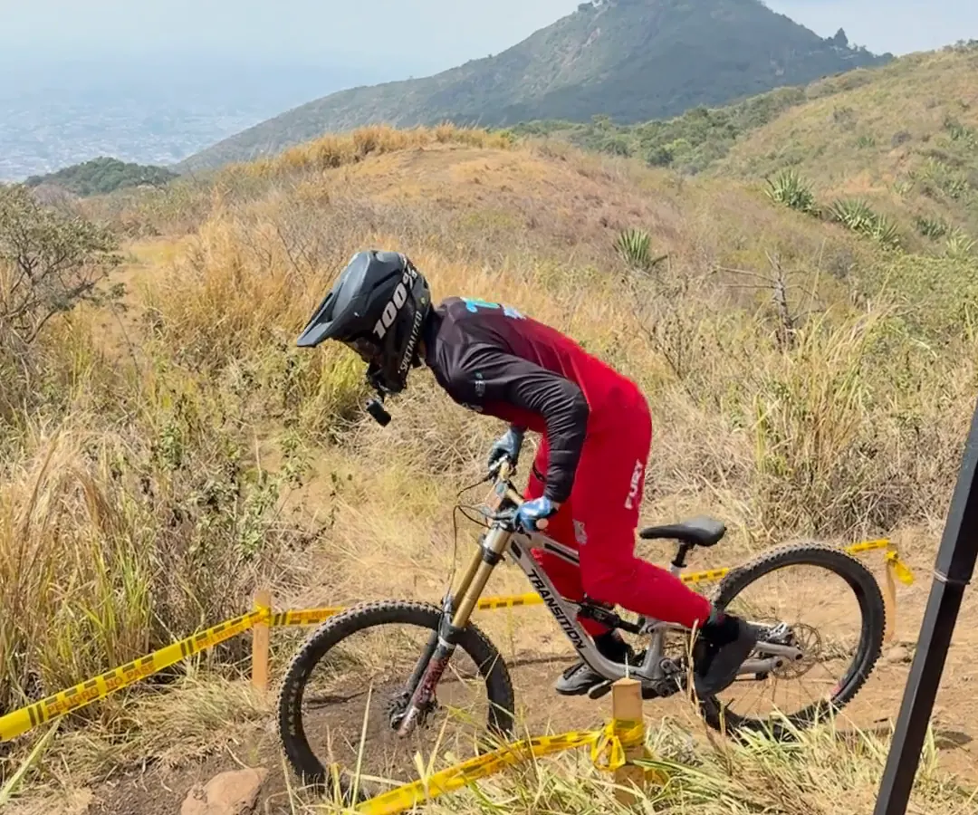 Juan Esteban Ortiz del Club Trocha y Ruta arranca en la salida de la Copa Cali Bike Park, de pie sobre los pedales, con un cerro al fondo, 2026