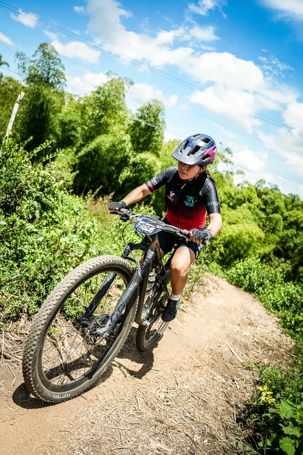 Isabel Quiñones del Club Trocha y Ruta, dorsal 604, toma una curva de tierra entre guaduales en el circuito de la Copa Let's Go Interdepartamental XCO, Alcalá, 2026
