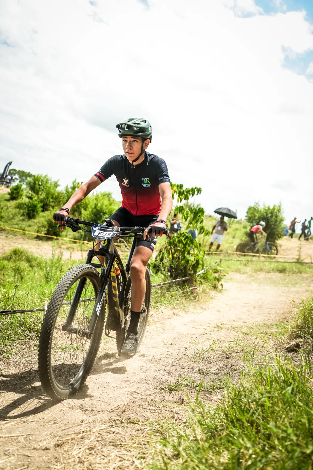 Samuel Ortiz del Club Trocha y Ruta, dorsal 3038, sube una loma de tierra junto al público en el circuito de la Copa Let's Go Interdepartamental XCO, Alcalá, 2026