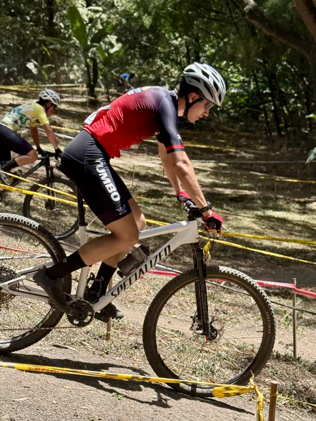 Juan Diego García inclinado sobre su bicicleta blanca Specialized, tomando una curva del circuito de XCO entre los árboles del Bosque Municipal