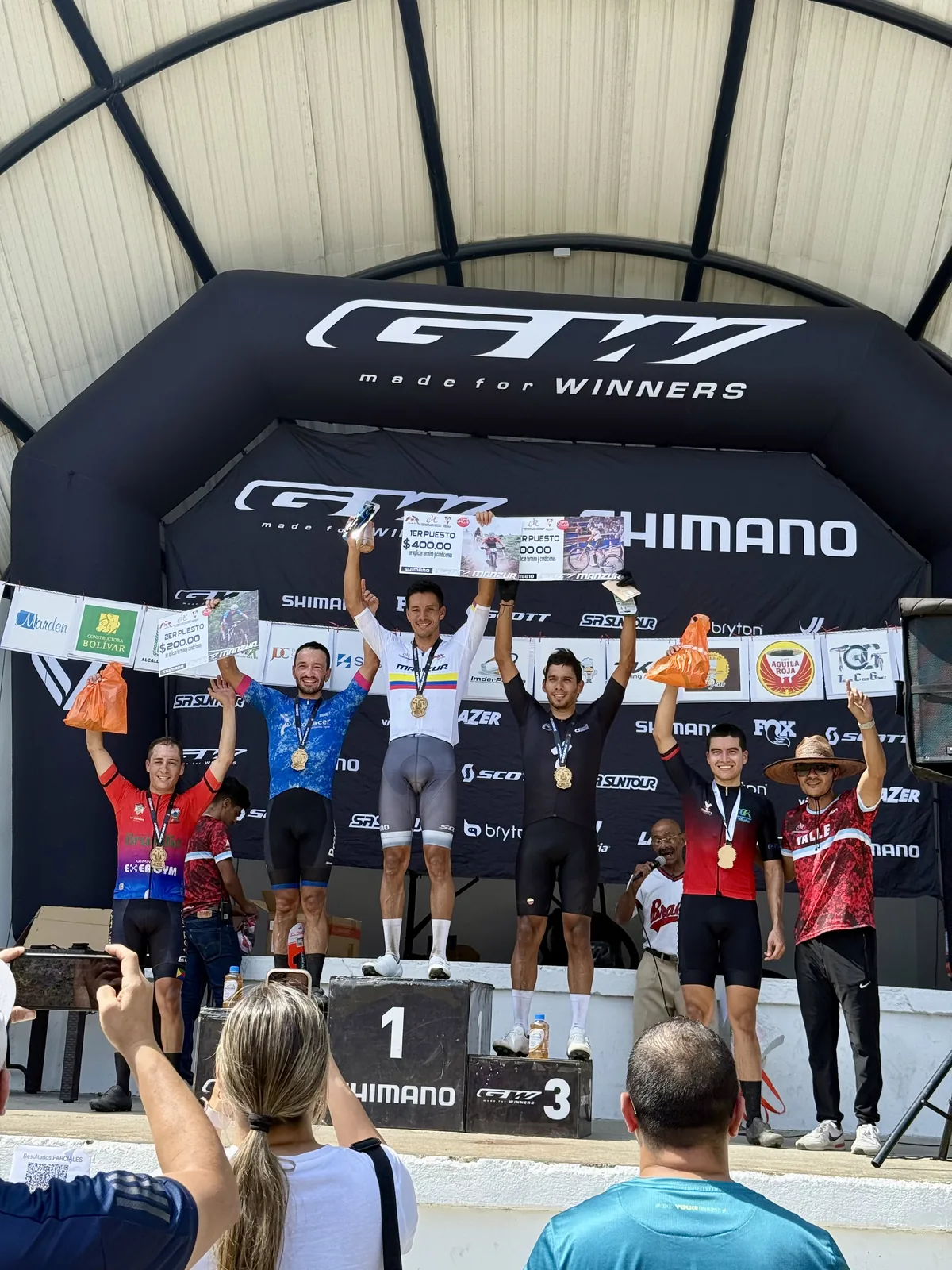 Premiación de la categoría Élite bajo el pórtico de meta, con los cinco primeros levantando los brazos y sus medallas