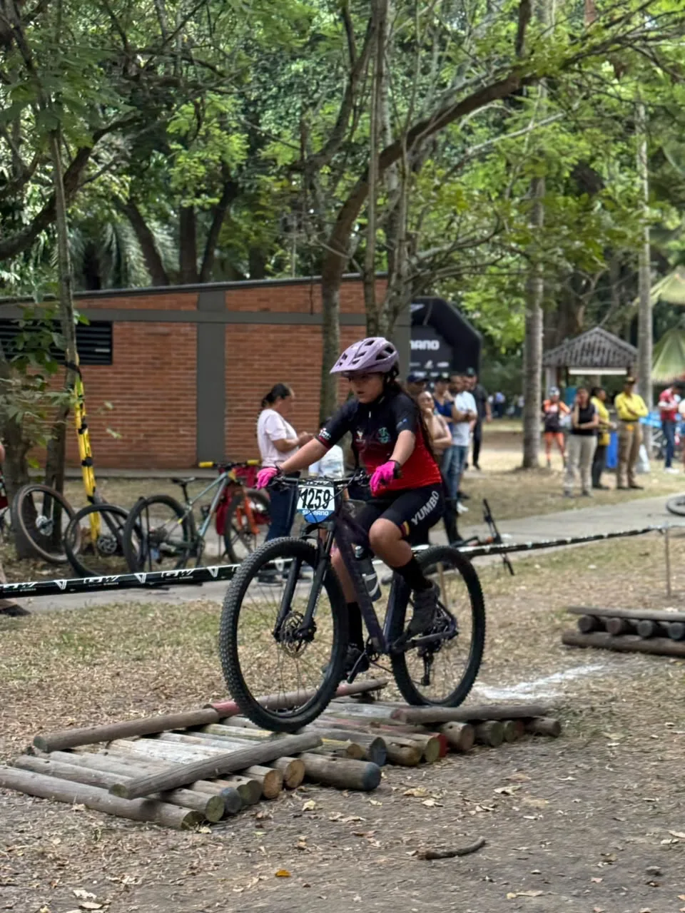 Sophia Vargas sobre su bicicleta cruza el obstáculo de troncos del circuito de gymkanas en el Bosque Municipal de Palmira